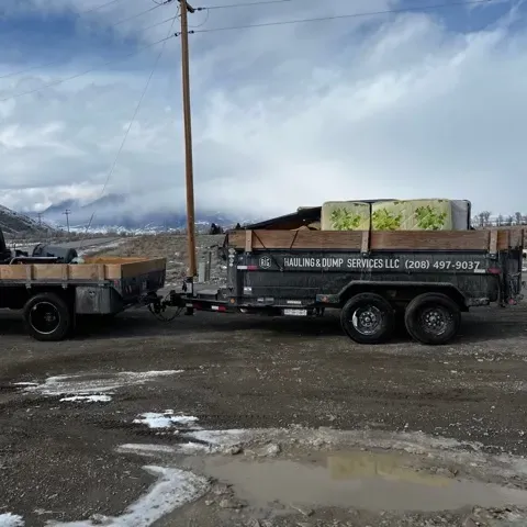 a truck with a trailer attached to it is parked on a dirt road .