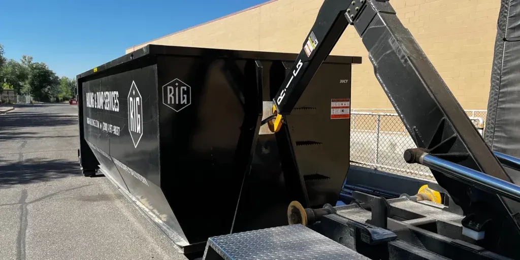 a dumpster is being towed down a street by a truck .