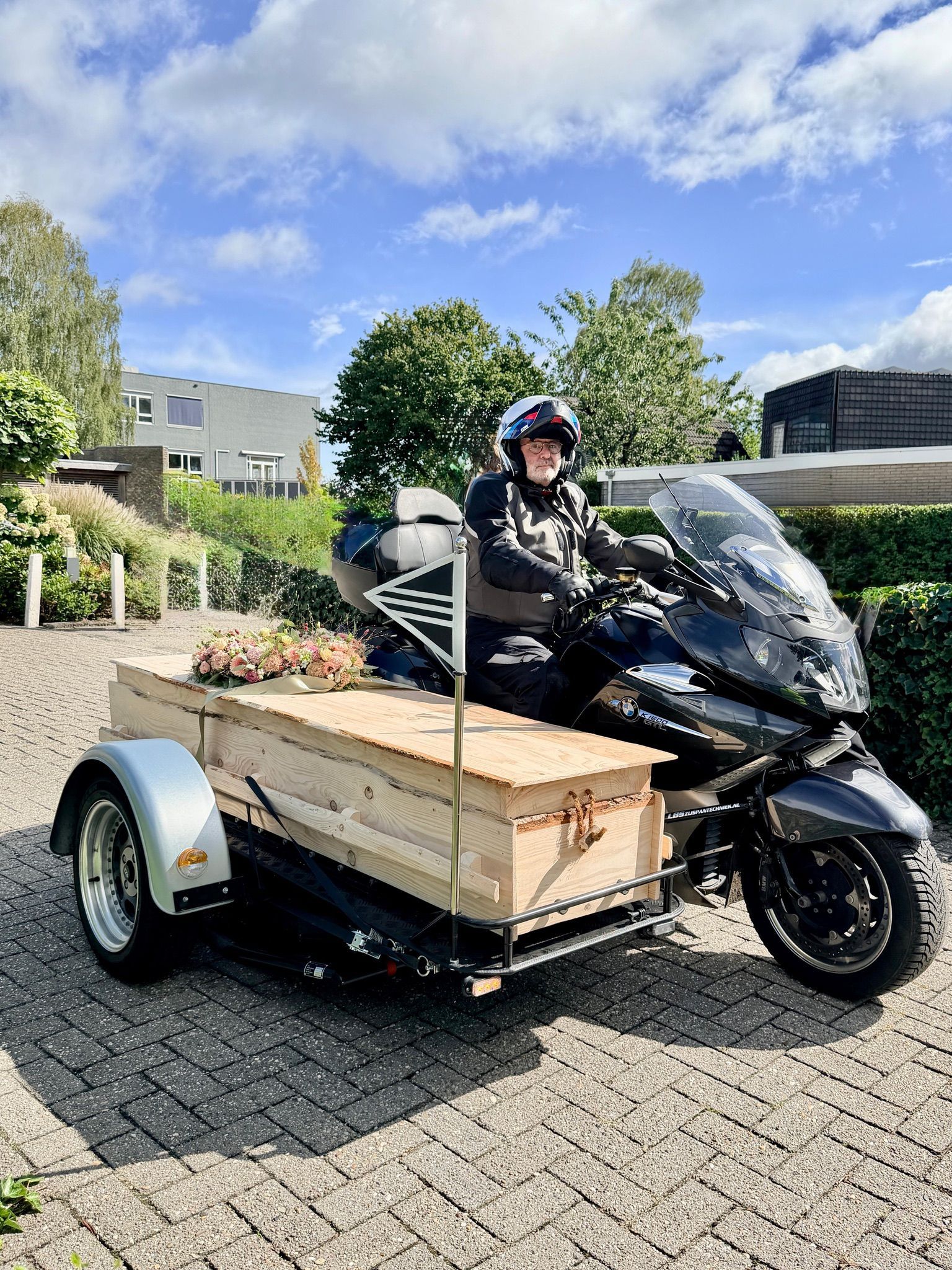 Uitvaartkist met bloemen op het zijspan van de BMW rouwmotor