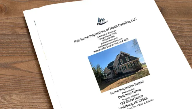 A brochure with a picture of a house on it is sitting on a wooden table.
