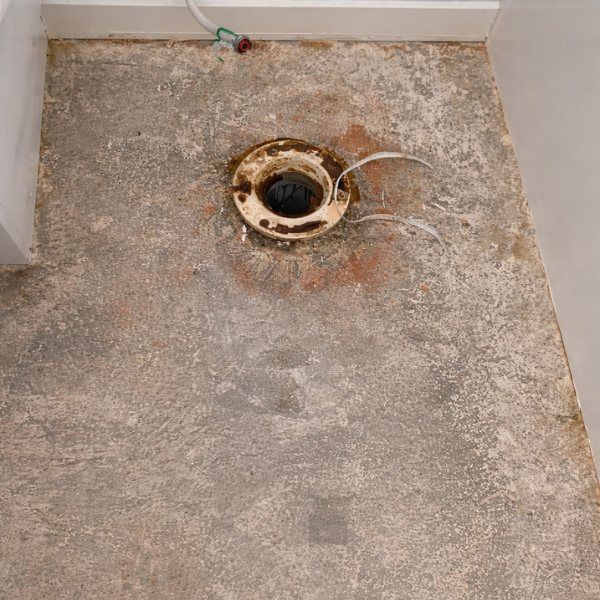 Toilet flange on a rough concrete floor; ready for installation.
