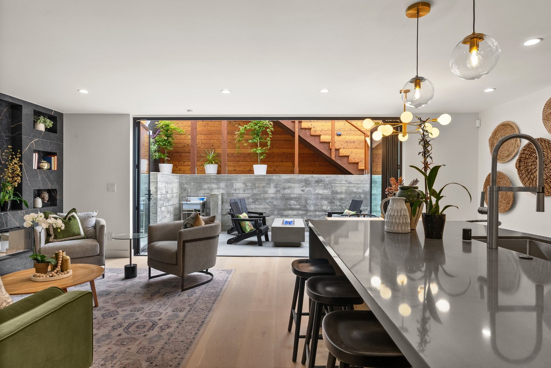 Modern open-plan living room and kitchen with gray chairs, island, and large glass doors to a patio