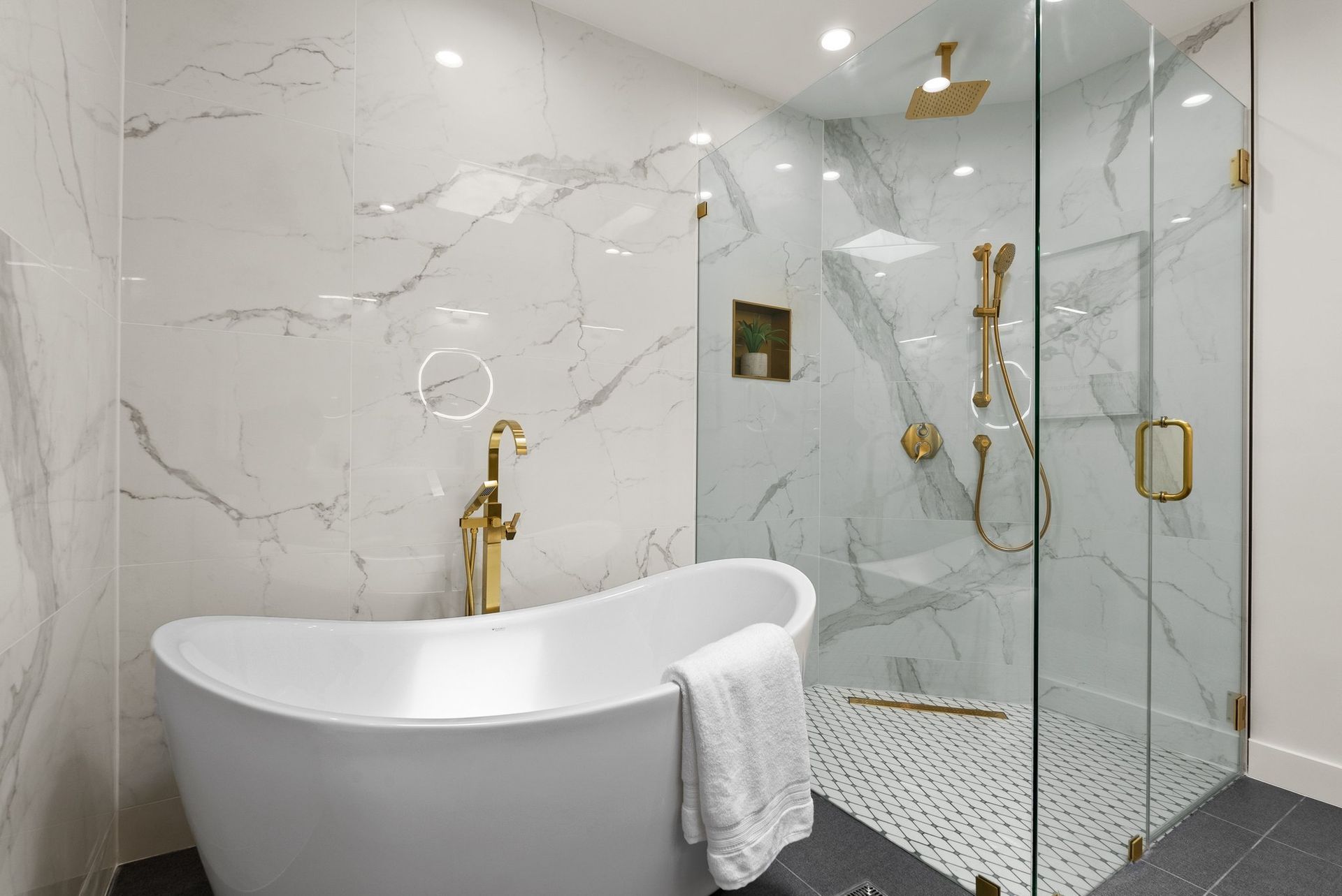 Modern white bathroom with freestanding tub, glass shower, and gold fixtures