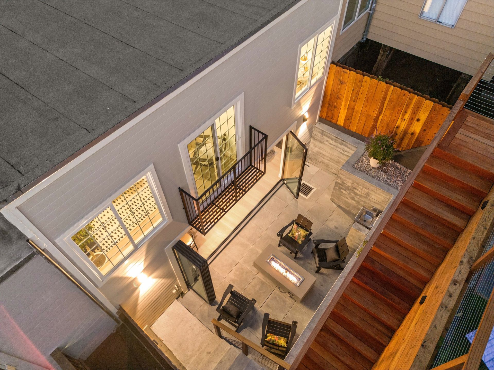 Courtyard patio with outdoor seating, string lights, and stairs beside a building at dusk