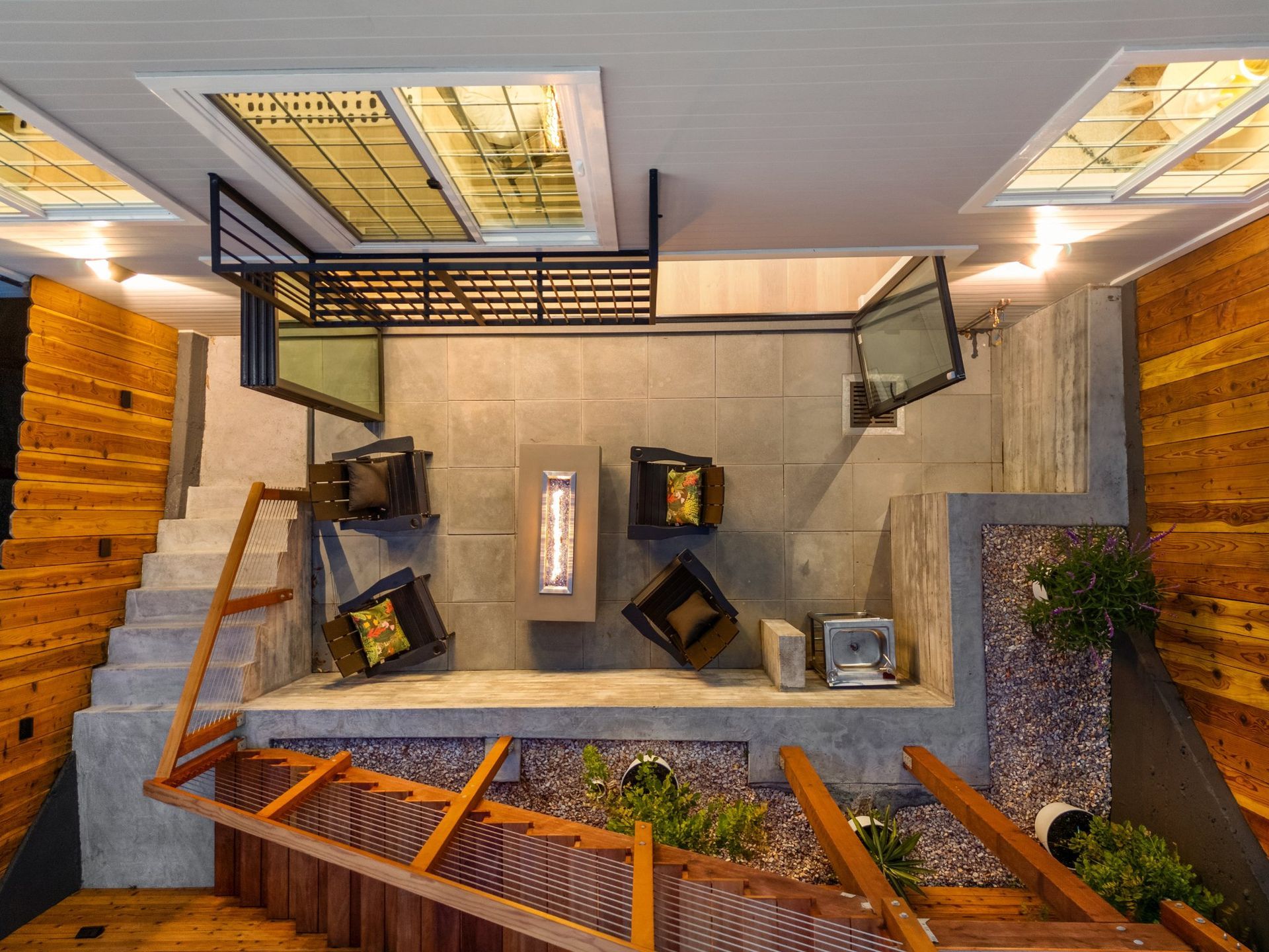 Top-down view of a modern atrium with seating, stone floor, skylights, and wood accents