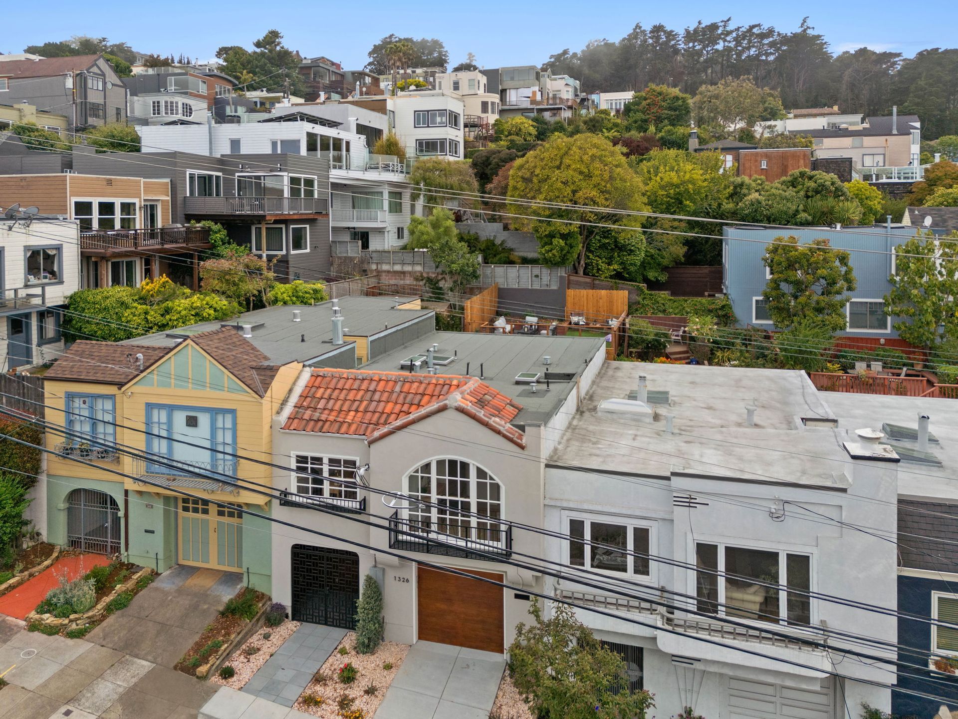 Hillside neighborhood with colorful houses and trees under an overcast sky