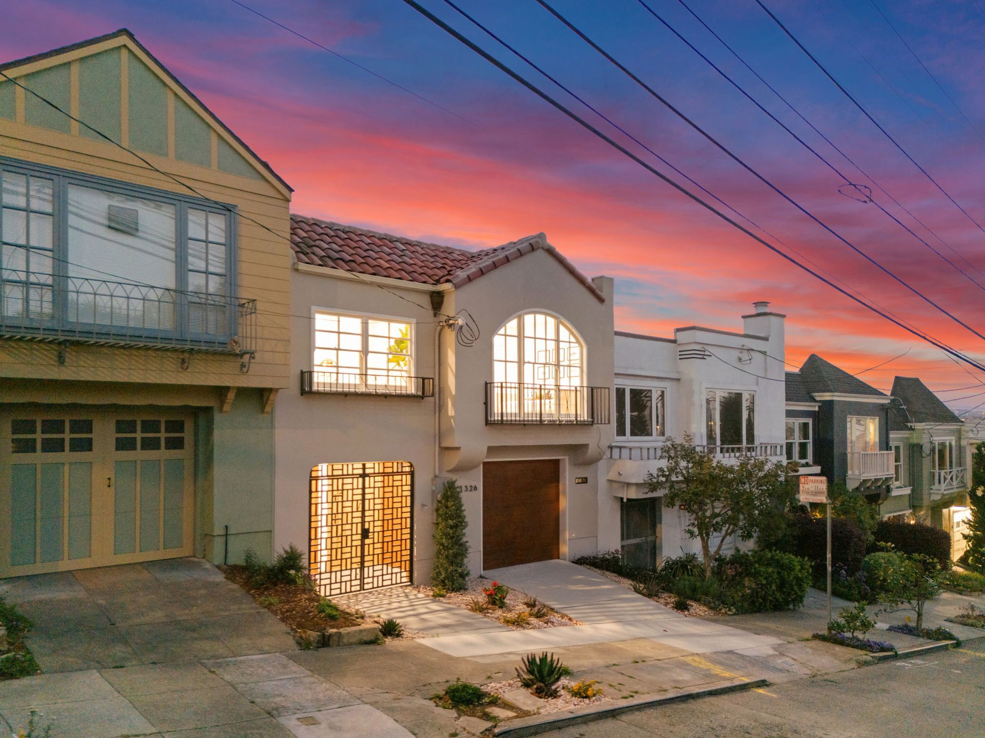 Modern suburban homes at sunset with lit windows and pink-orange sky