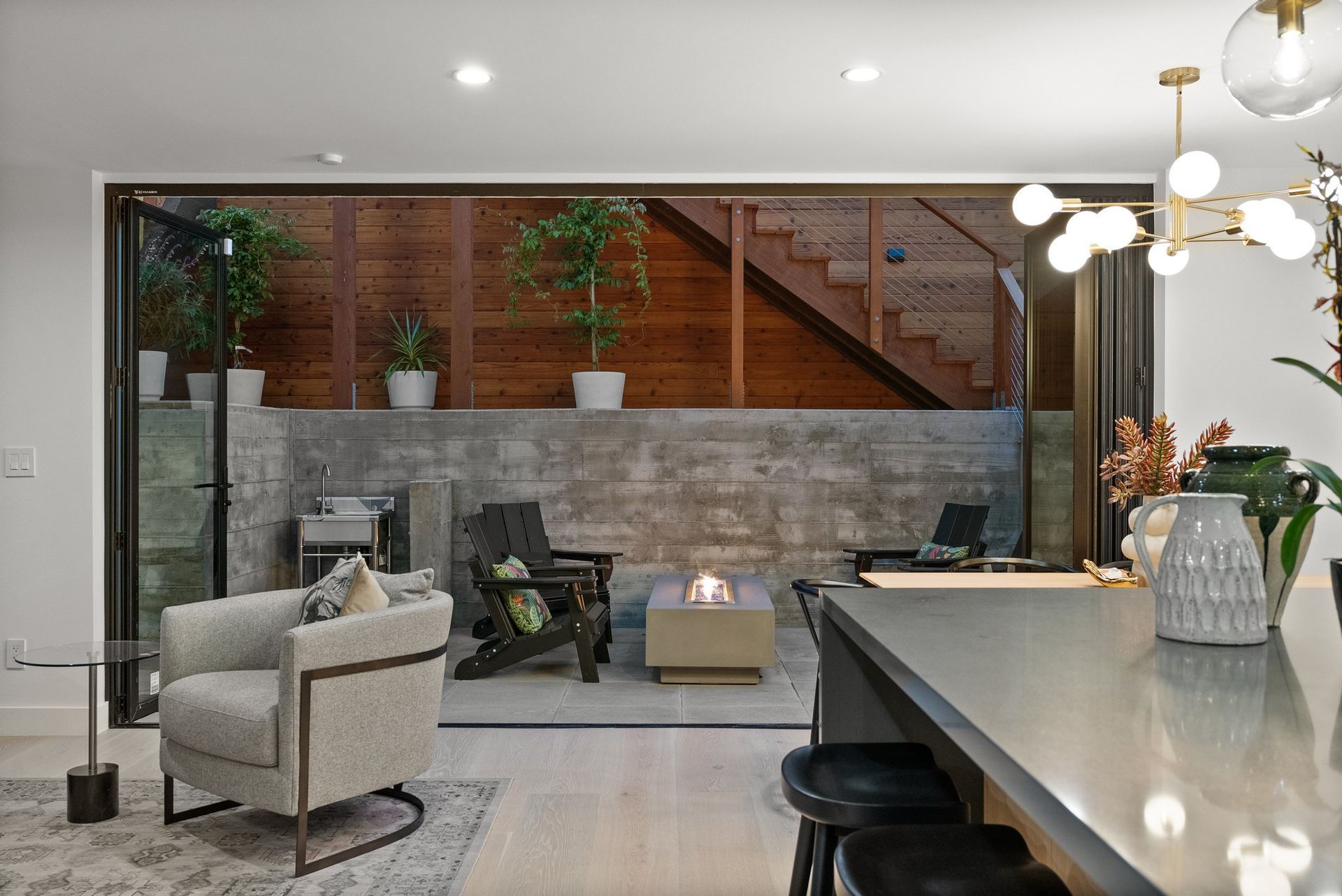 Modern living room with glass partition, beige chairs, fireplace, and kitchen island in the foreground