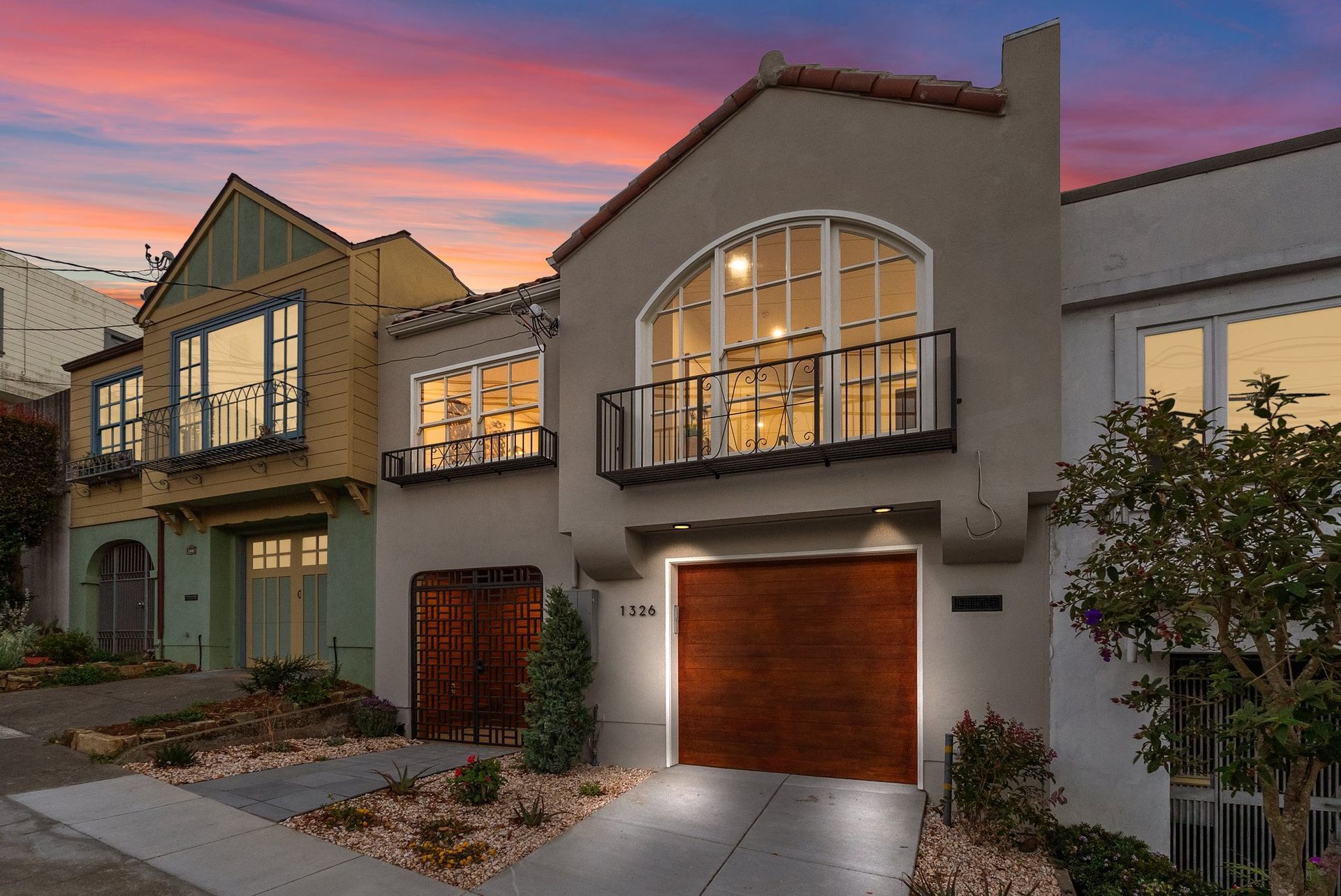 Modern townhouse row at sunset with lit windows and a garage in front