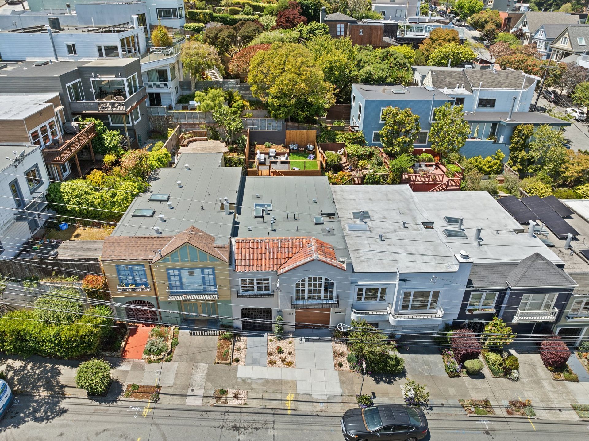 Aerial view of row houses with red and gray roofs on a tree-lined residential street