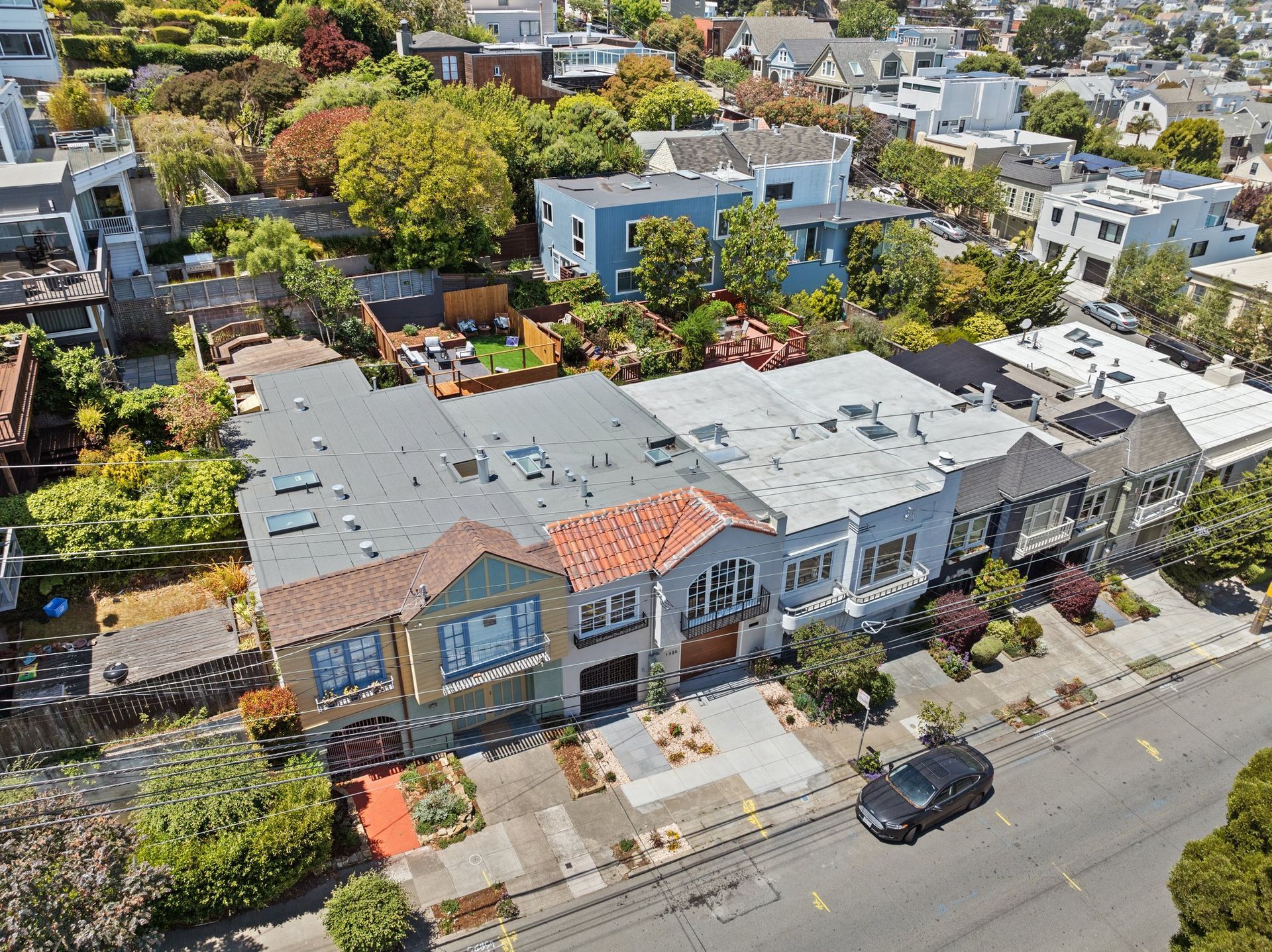 Aerial view of a row of colorful townhouses on a leafy residential street