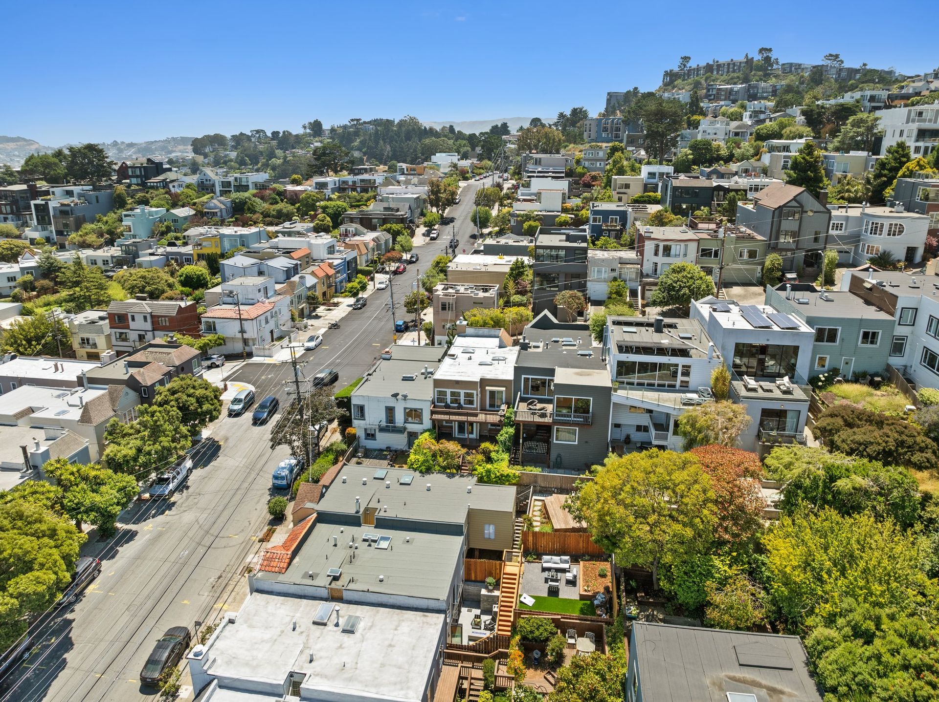 Aerial view of a hillside neighborhood with homes, tree-lined streets, and a road running through it