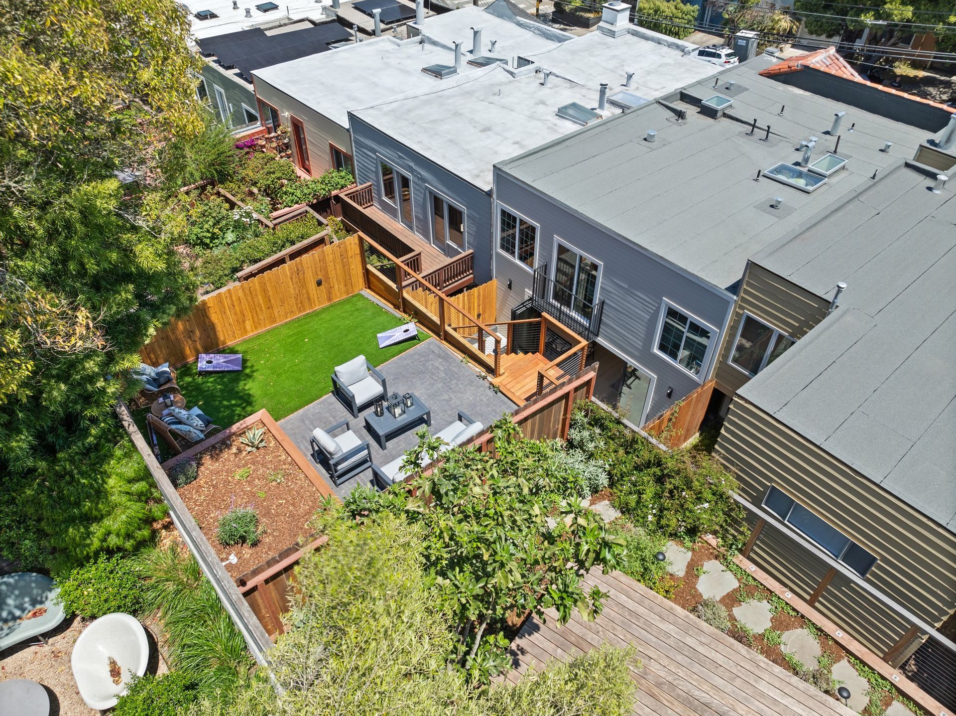 Aerial view of a modern backyard with patio furniture, green lawn, and wooden fence beside a house