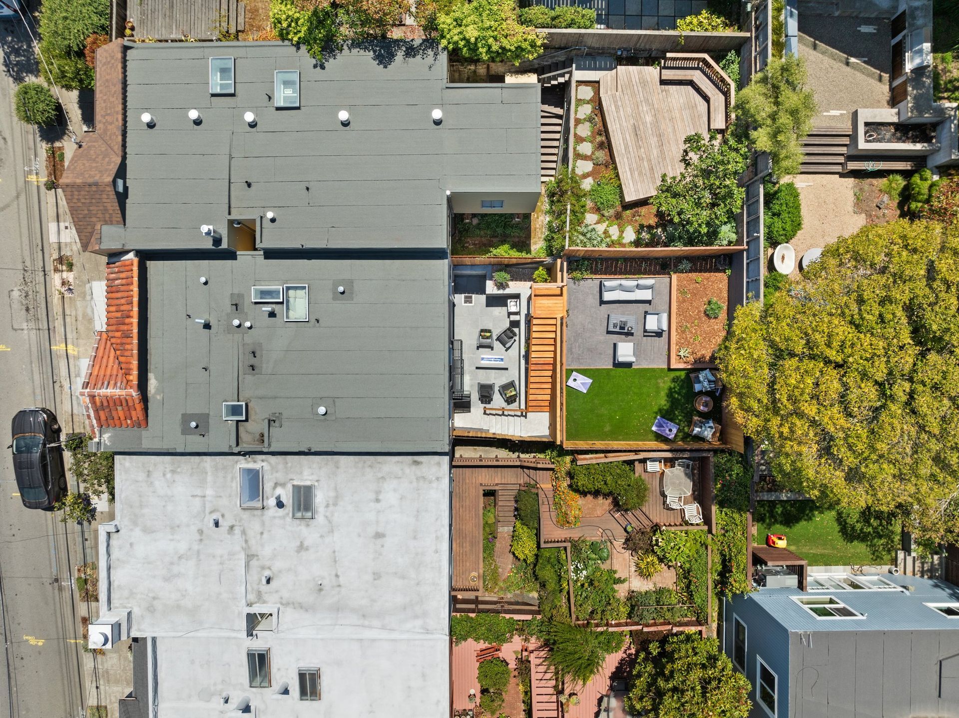 Aerial view of residential rooftops, a backyard patio, and lush trees in a neighborhood