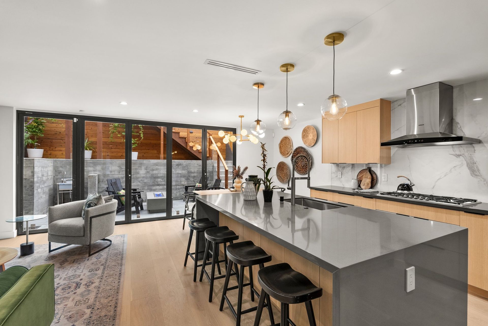 Modern open kitchen with large island, bar stools, pendant lights, and sliding glass doors to a patio