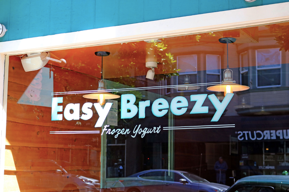 Easy Breezy Frozen Yogurt shop sign on a storefront window with orange and blue accents