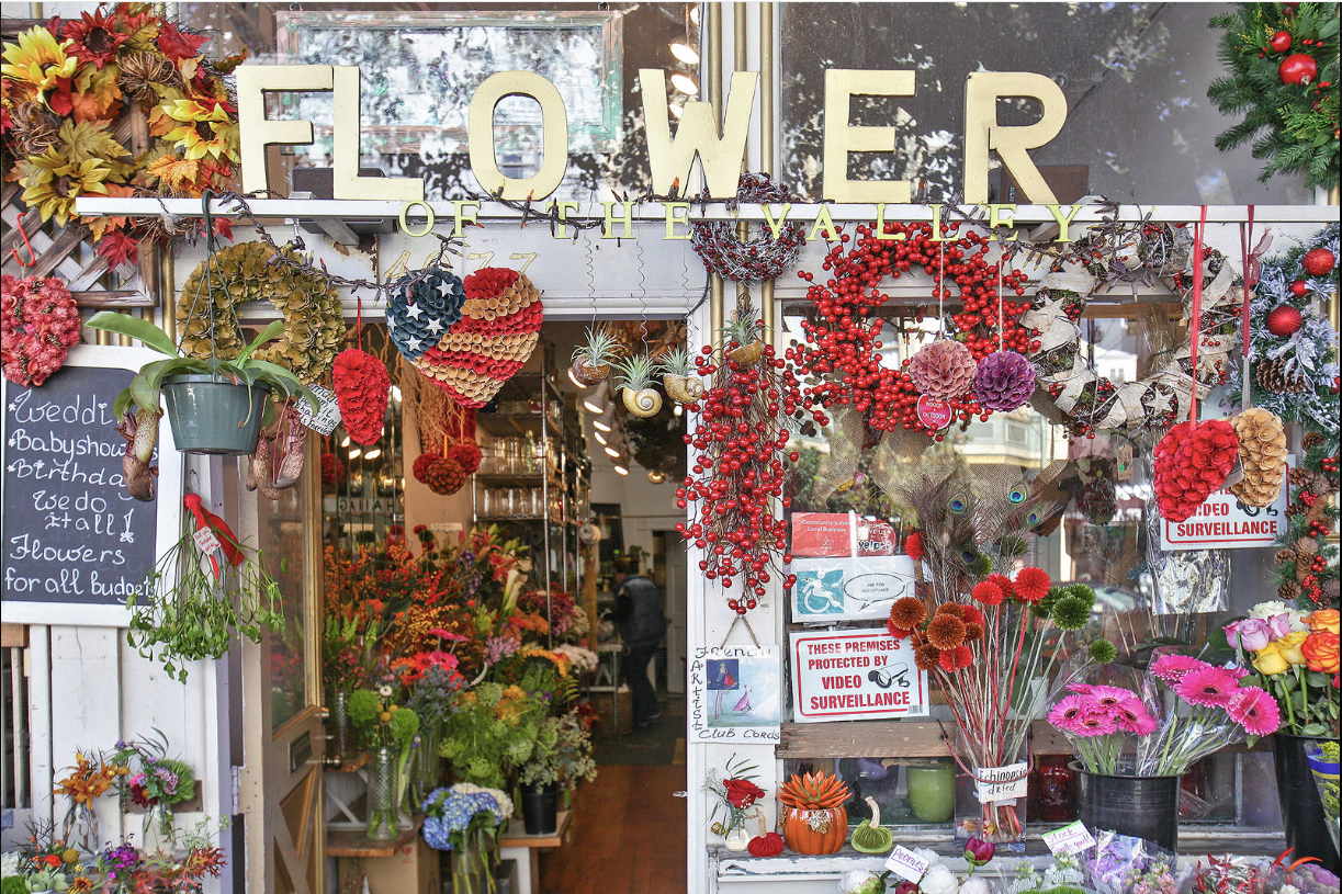 Flower shop storefront filled with colorful bouquets and hanging floral wreaths
