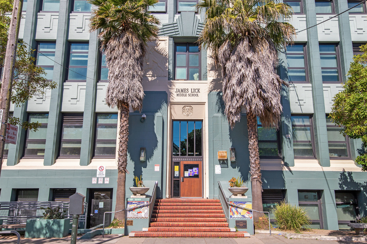 Art Deco building facade with a red brick staircase, palm trees, and blue-trimmed windows