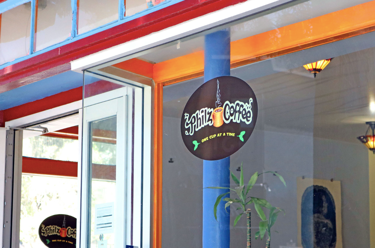 Storefront with a round black hanging sign and blue-and-orange trim around an open doorway