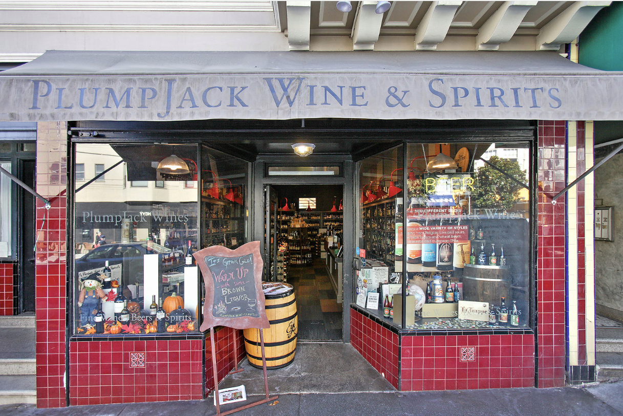 Wine and spirits shop storefront with red tile facade and display barrels in the entrance