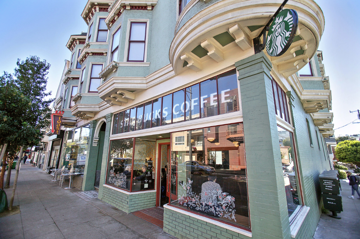 Corner coffee shop with large windows and teal trim on a city street corner