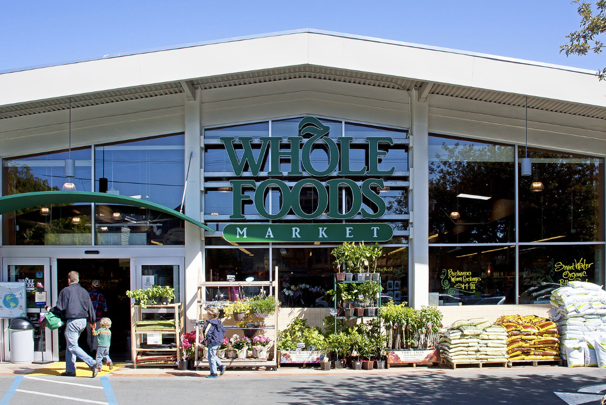 Whole Foods Market storefront with shoppers and outdoor plant displays