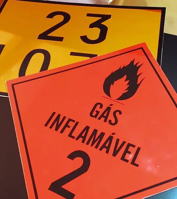 Red and yellow hazardous materials signs, including a red “GÁS INFLAMÁVEL 2” placard.