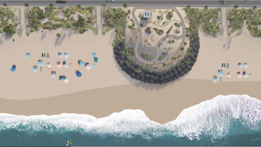 Aerial view of a beach resort with umbrellas, palm trees, and a circular garden beside the shoreline.