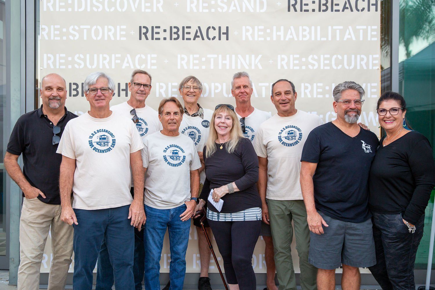 Group of volunteers standing together in front of a wall with recycling and reuse words.