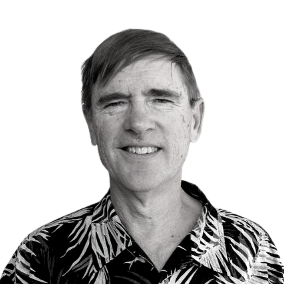 Man smiling in a black-and-white portrait, wearing a patterned Hawaiian shirt.