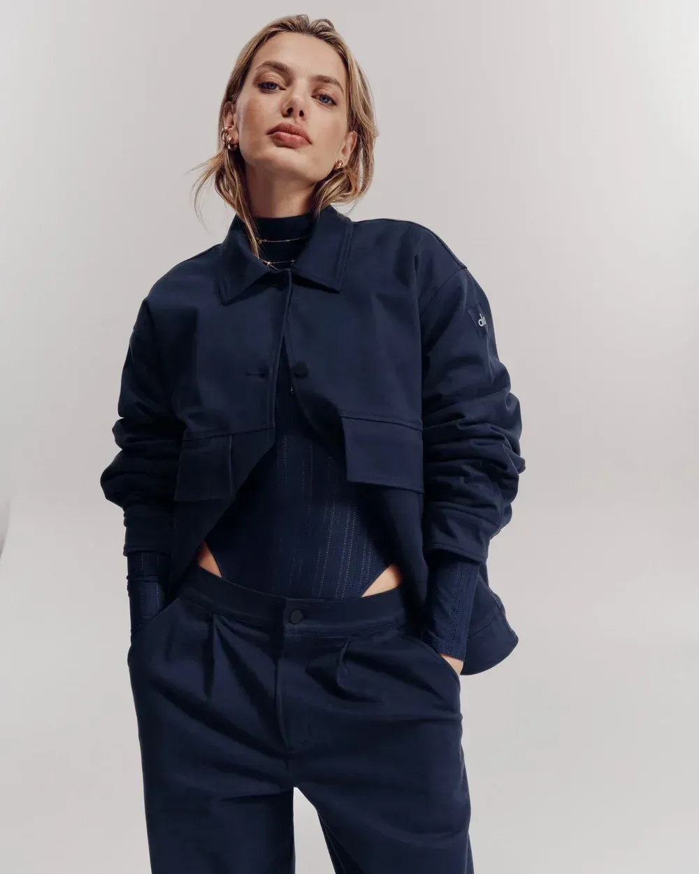 Model wearing a navy blue jacket and pants against a light gray background