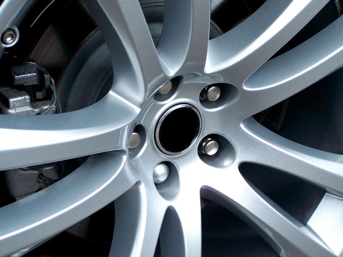 Cerchione d'argento per auto con più razze, disco del freno visibile sullo sfondo.