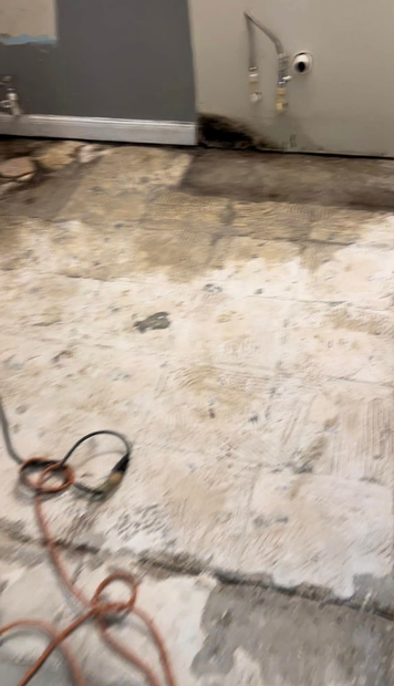 Partially demolished room floor with removed flooring, debris, and exposed walls in a renovation site