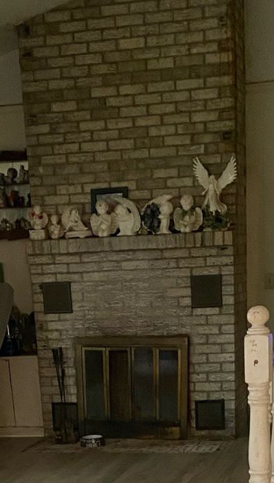Brick fireplace with glass doors, mantel figurines, and a white cat statue on the right