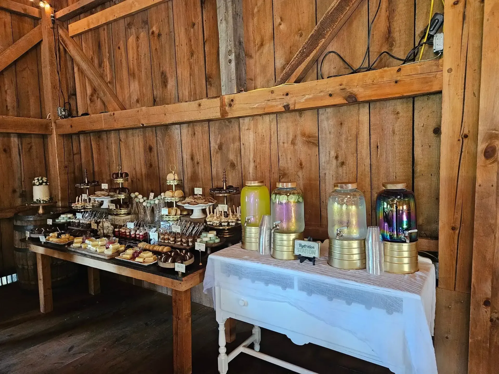 Buffet table with bottles and jars set against a rustic wooden barn wall