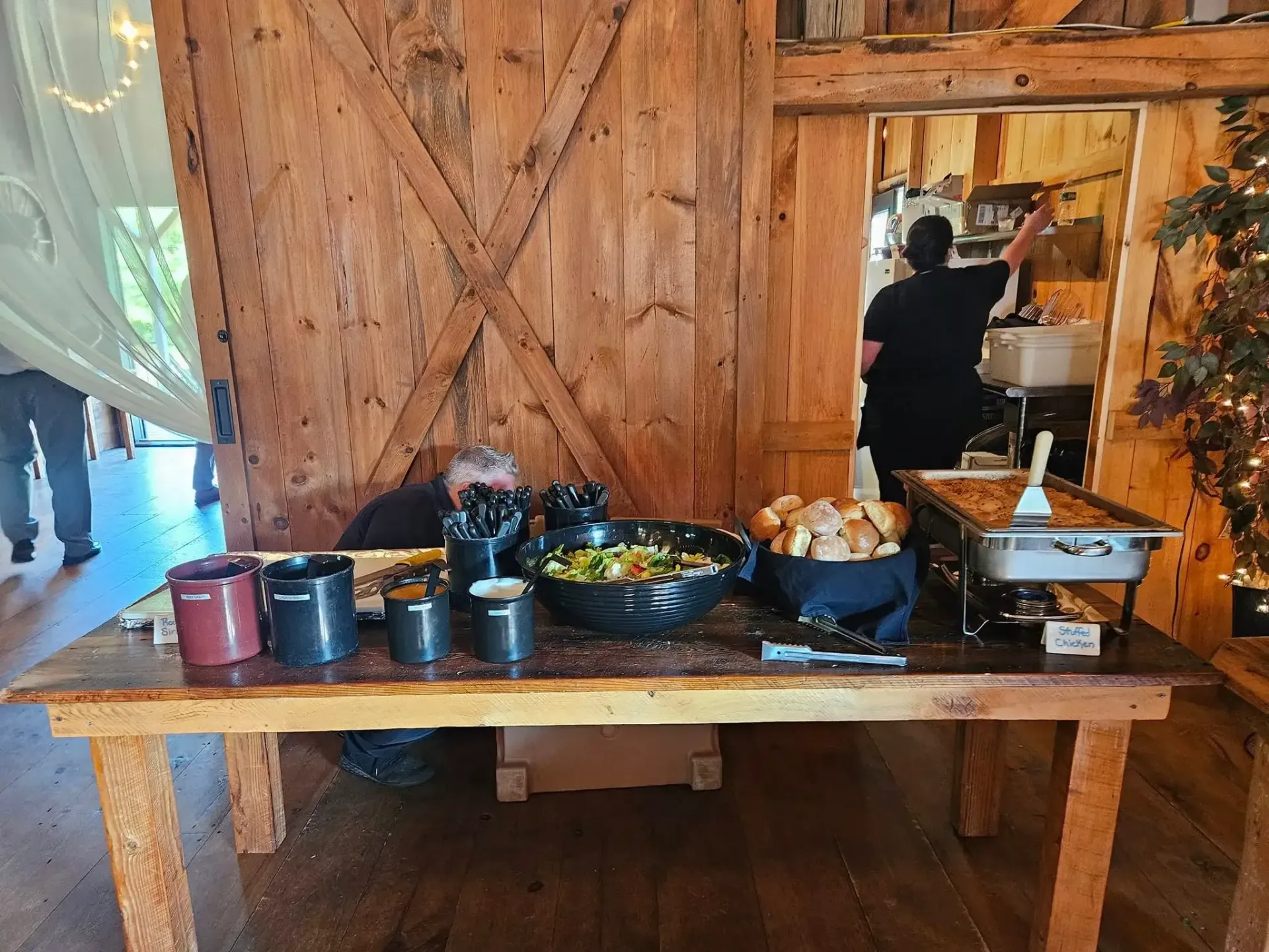 Buffet table with metal pots and serving dishes in a rustic wooden dining hall