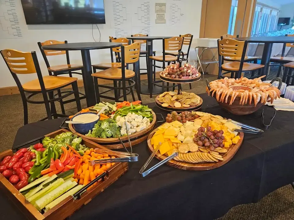 Buffet table with vegetables, dips, sliced meats, and pastries in a casual dining room