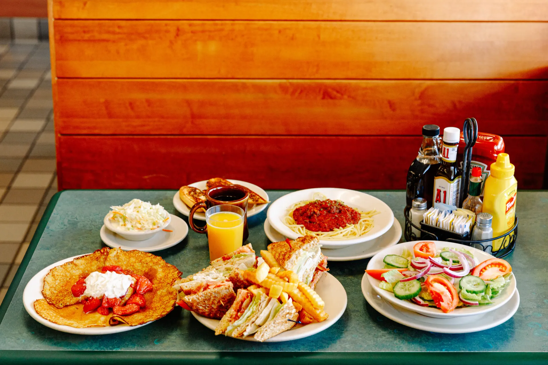 Assorted breakfast plates and drinks on a table in a restaurant booth