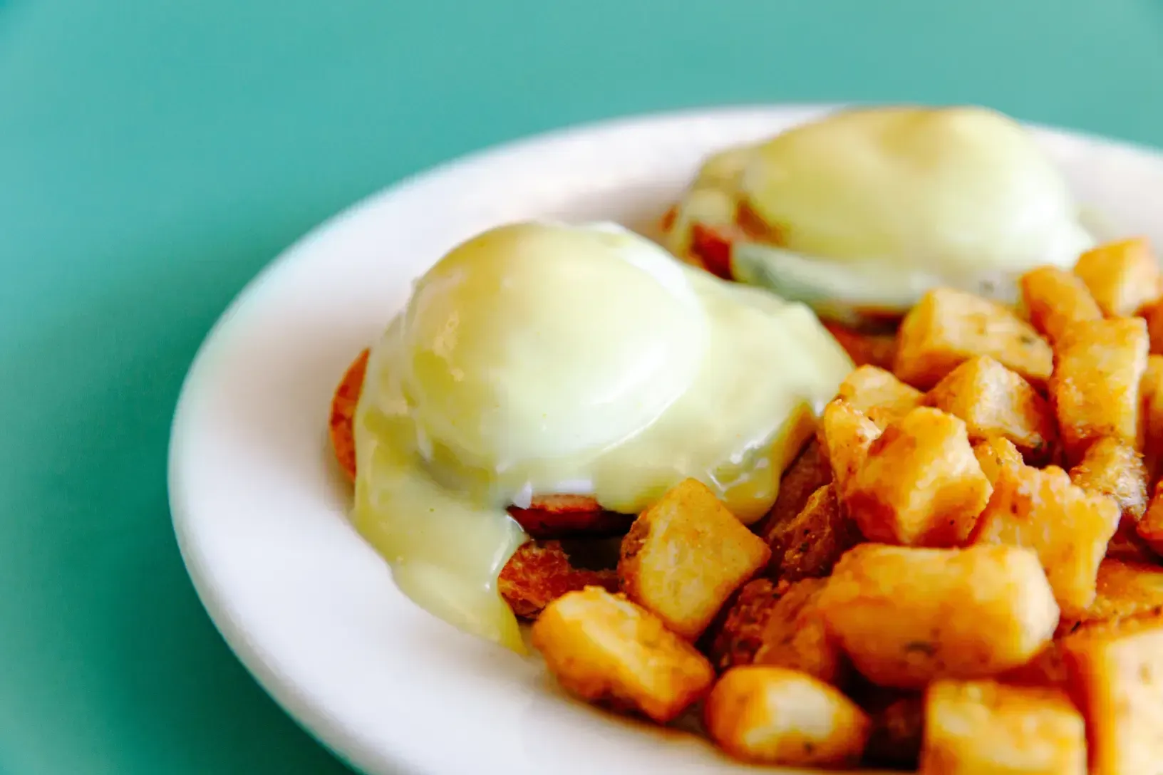 Two poached eggs on toast with diced potatoes on a white plate
