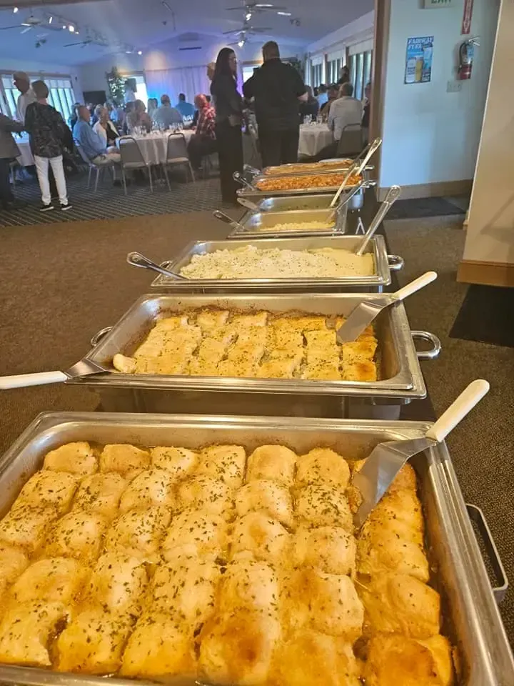 Buffet table with trays of bread and baked dishes at a banquet hall reception