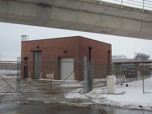 A brick building behind a fence with a sign that says no parking