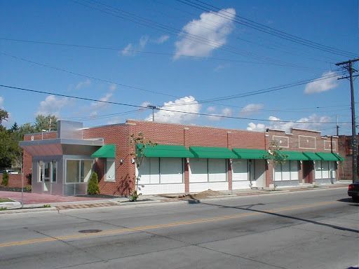 A brick building with green awnings on the windows