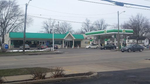 A gas station with a green roof and cars parked in front of it.