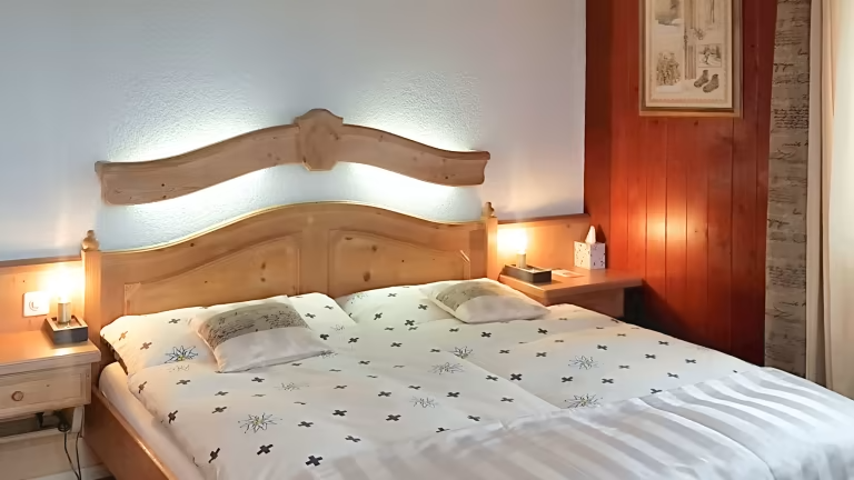 Chambre avec un lit double, une tête de lit en bois, des tables de chevet et des lampes. Décorations murales rouges et œuvres d'art encadrées.