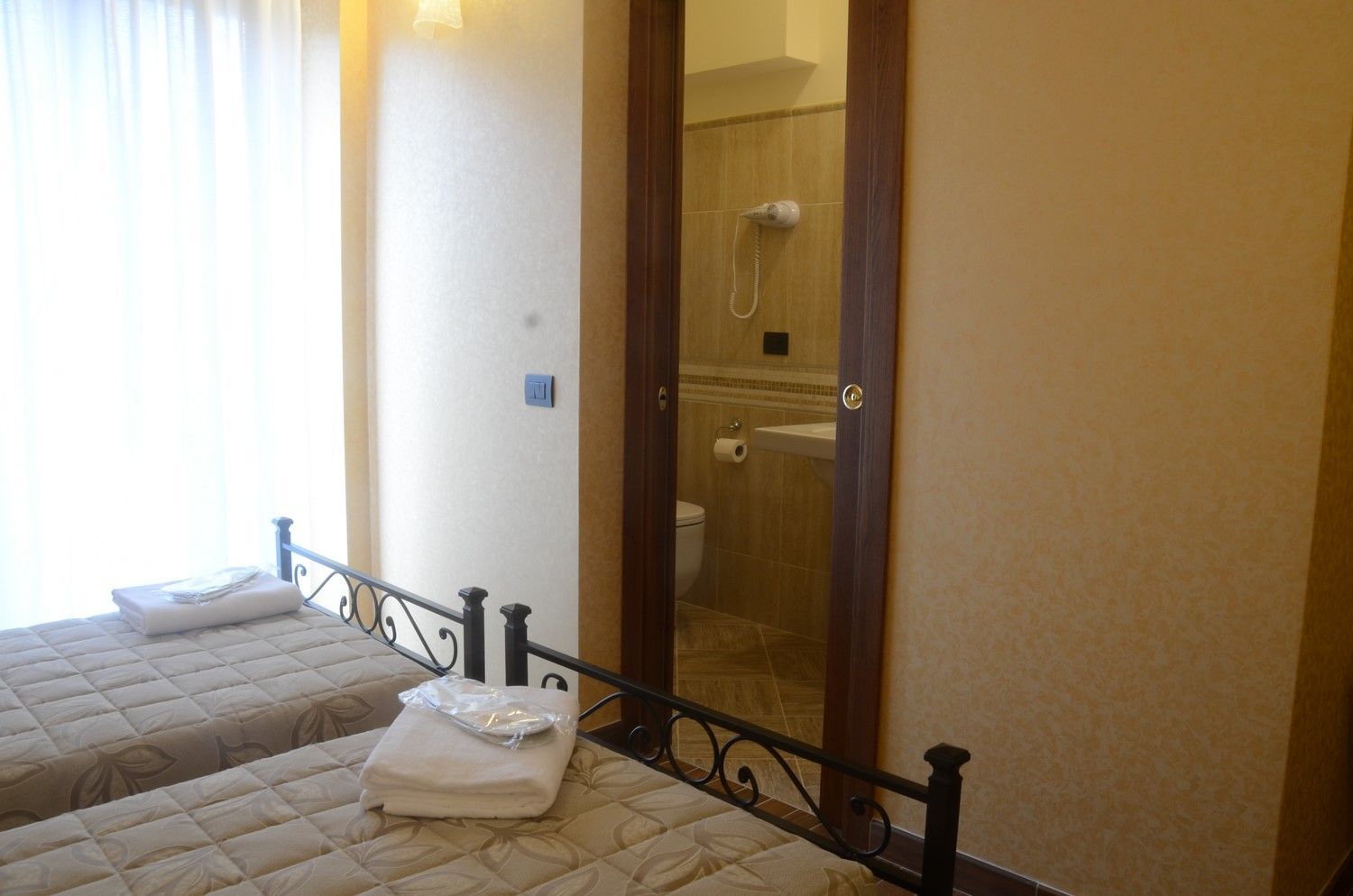 Camera da letto con due letti singoli e doccia con porta in vetro nell'angolo.