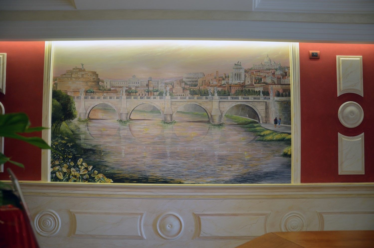 Murale raffigurante un ponte di pietra su un fiume, incorniciato da pareti rosse e modanature decorative all'interno.