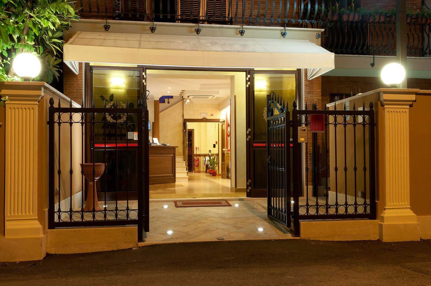 Ingresso dell'edificio illuminato di notte con cancello aperto e luci interne calde