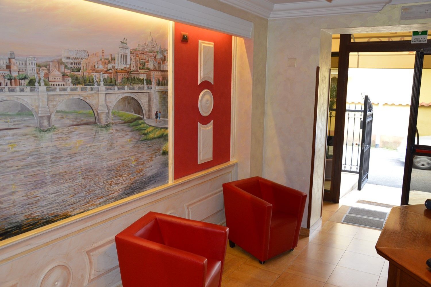 Sedie rosse in una stanza luminosa con un grande murale e una porta che dà su un patio.