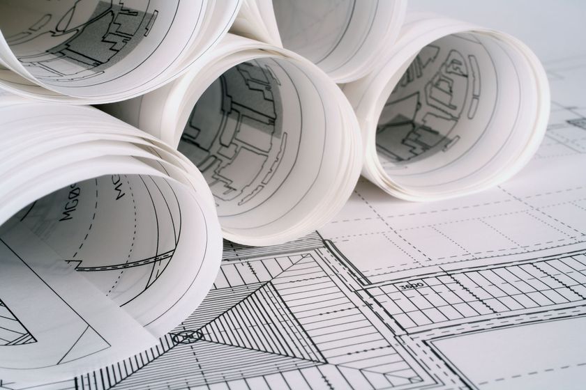 Plusieurs rouleaux de plans architecturaux posés sur un plan d'étage plat et détaillé.
