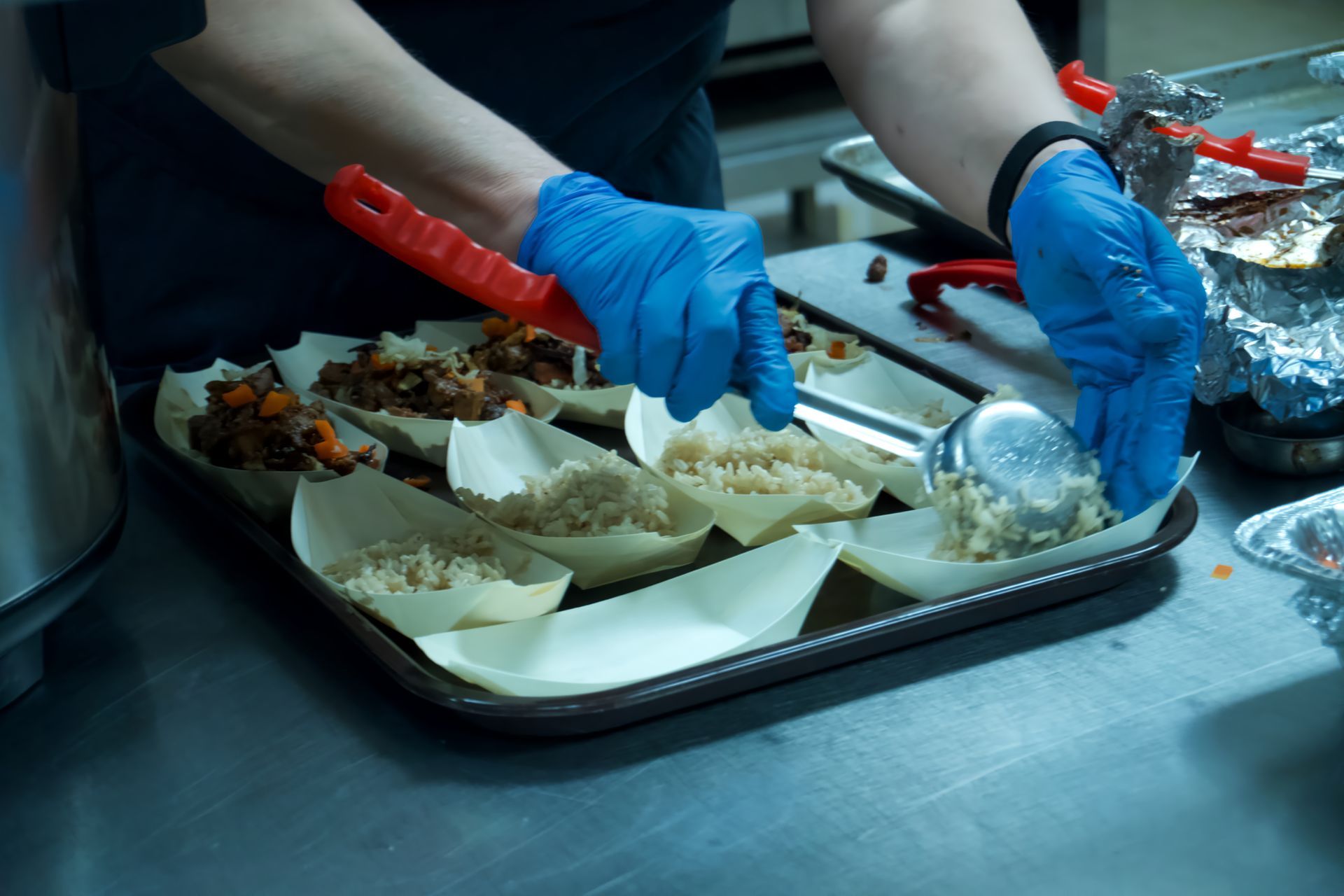 A person wearing blue gloves is preparing food on a tray